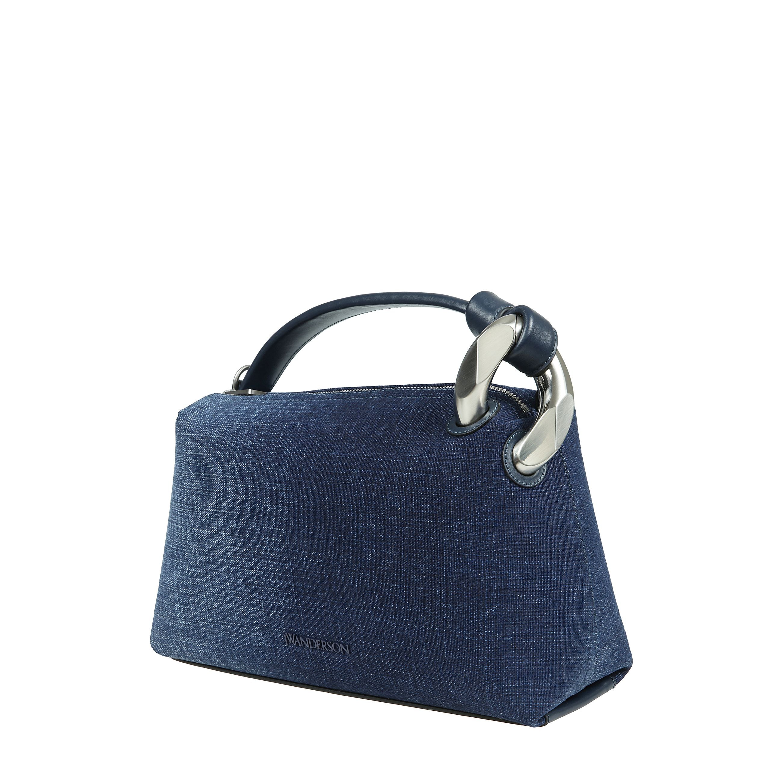 Vi presentiamo la borsa portatile della collezione esclusiva di jw anderson. questo sofisticato accessorio è un capolavoro di design contemporaneo, caratterizzato da una forma triangolare leggermente arrotondata con eleganti linee dritte. la sua superfic