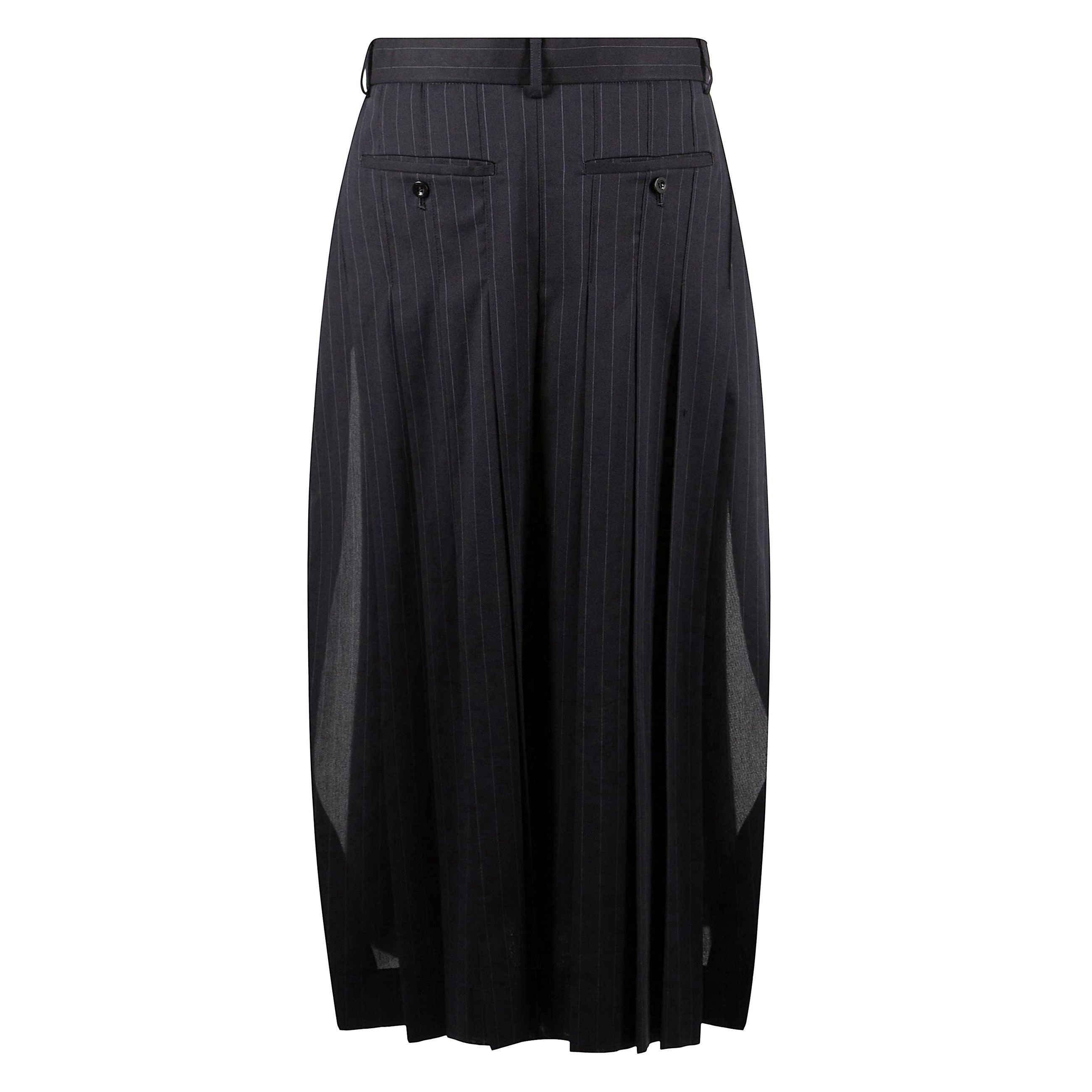 E' un capo realizzato in pura lana nera, presenta un design strutturato e asimmetrico, con una lunghezza mini. le caratteristiche includono tasche laterali, un sottogonna visibile con dettagli a contrasto, spacchi laterali e un orlo asimmetrico. la chiusu