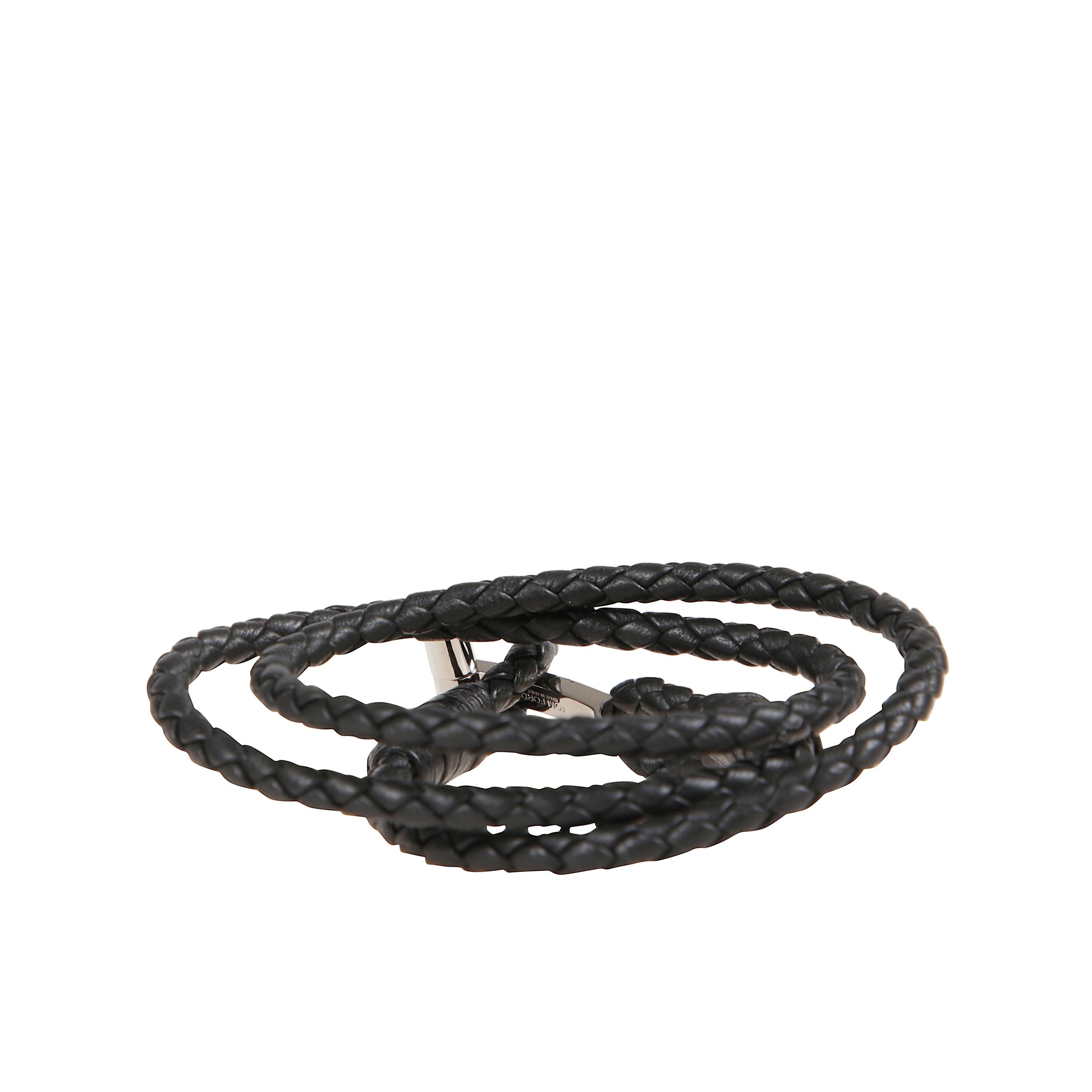 Bracciale in pelle a fascia intrecciata. chiusura ad alamaro con placca in bronzo metallizzato che riporta il simbolo tom ford.