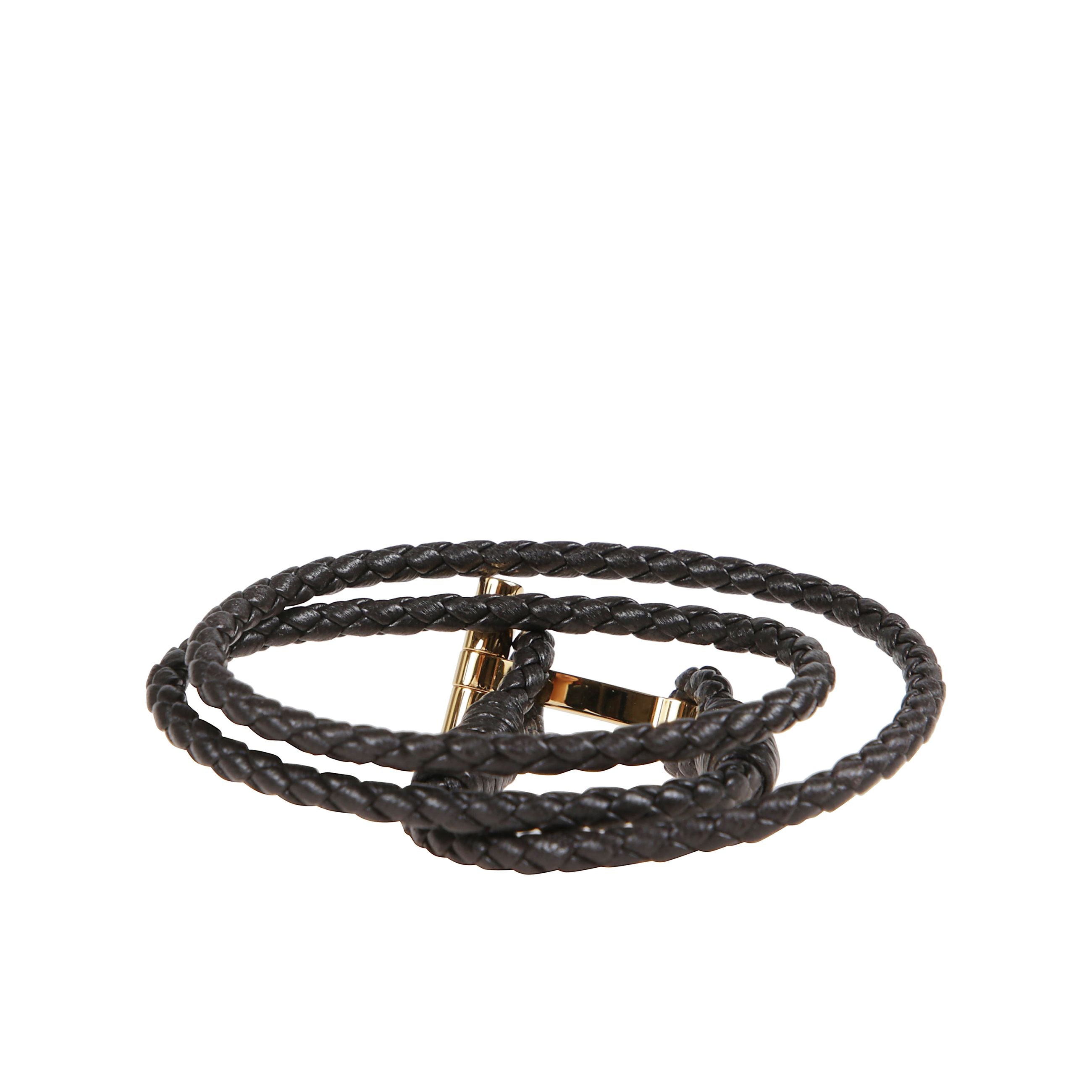 Bracciale in pelle a fascia intrecciata. chiusura ad alamaro con placca in bronzo dorato che riporta il simbolo tom ford.