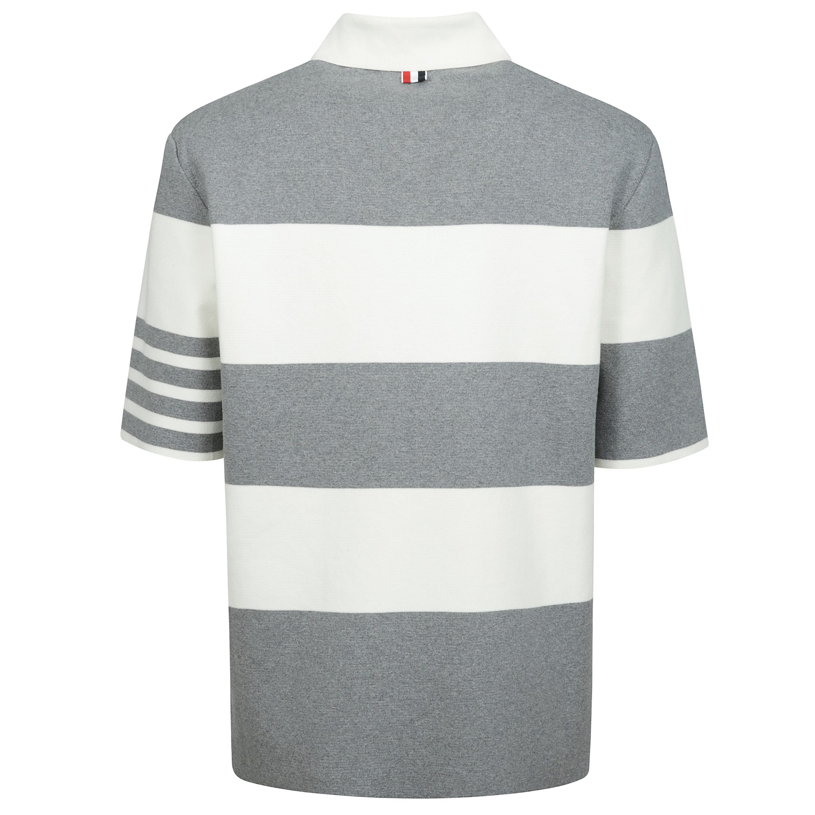La maglia polo milano in cotone di thom browne è un capo dallo stile elegante e distintivo. presenta un colletto classico e una chiusura frontale con bottoncini, mentre gli spacchi laterali aggiungono un tocco di dinamismo al design. la fantasia a righe