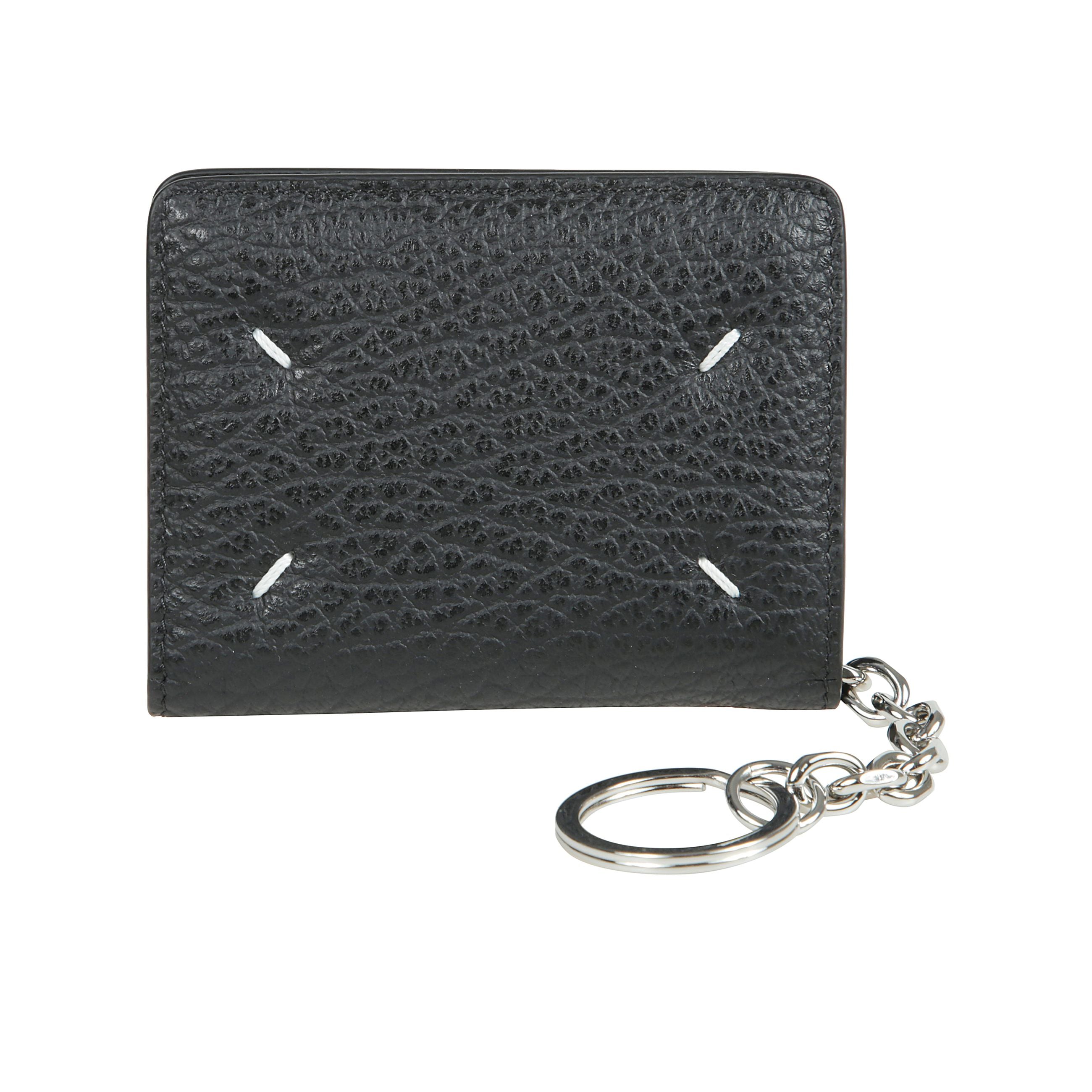 Portacarte in pelle martellata, con portachiavi, bottone automatico di chiusura e vari scomparti portatessere. sul retro, spiccano four stitches, caratteristica indiscussa di maison margiela : lâopposto di unâetichetta.