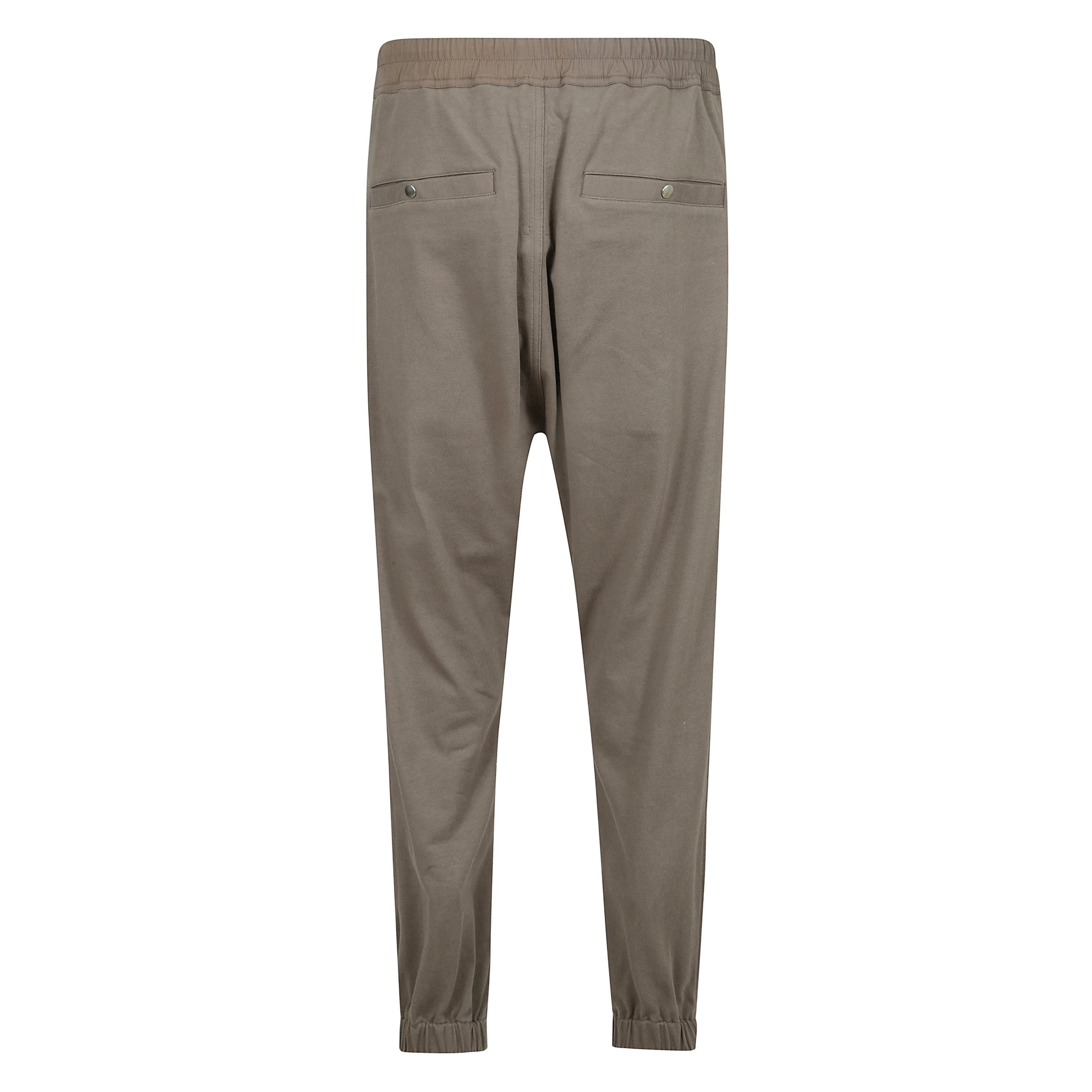 I tecuatl track pants di rick owens coniugano estetica urban e design d’avanguardia. realizzati in cotone organico, presentano una silhouette affusolata con cavallo leggermente ribassato, vita elasticizzata con coulisse e chiusura con bottoni in corno d