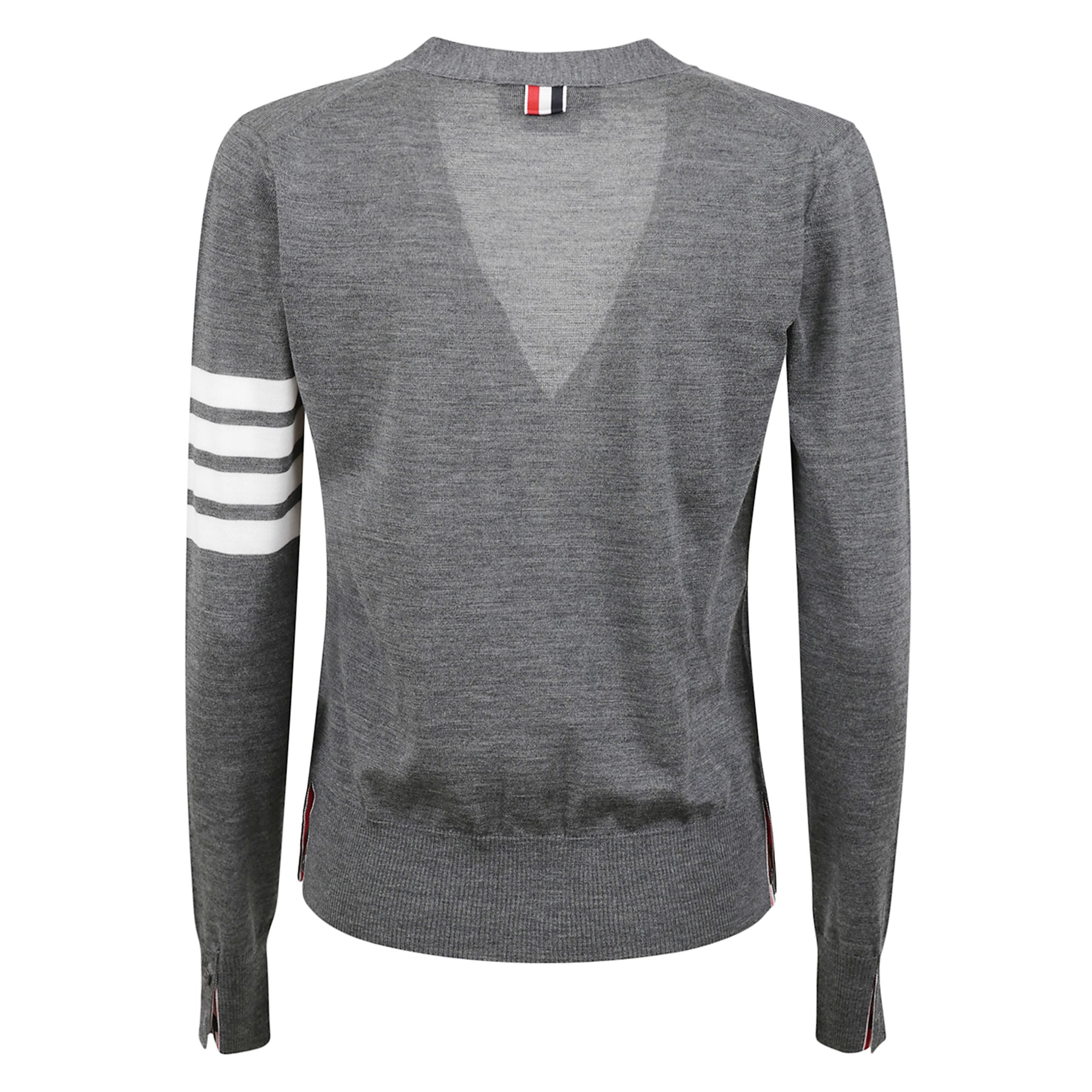 Cardigan in lana merino con scollo a v. vestibilità rilassata. chiusura con bottoni. dettaglio a quattro barre sulla manica. polsini e orlo elasticizzati a costine con bottoncini. linguetta in grosgrain thom browne sul retro.