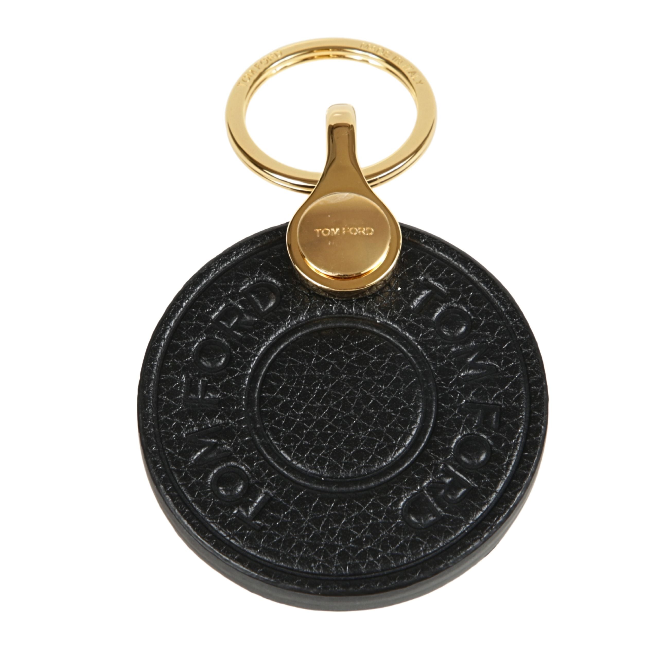 Portachiavi in pelle a forma circolare, con logo inciso e dettagli in oro.