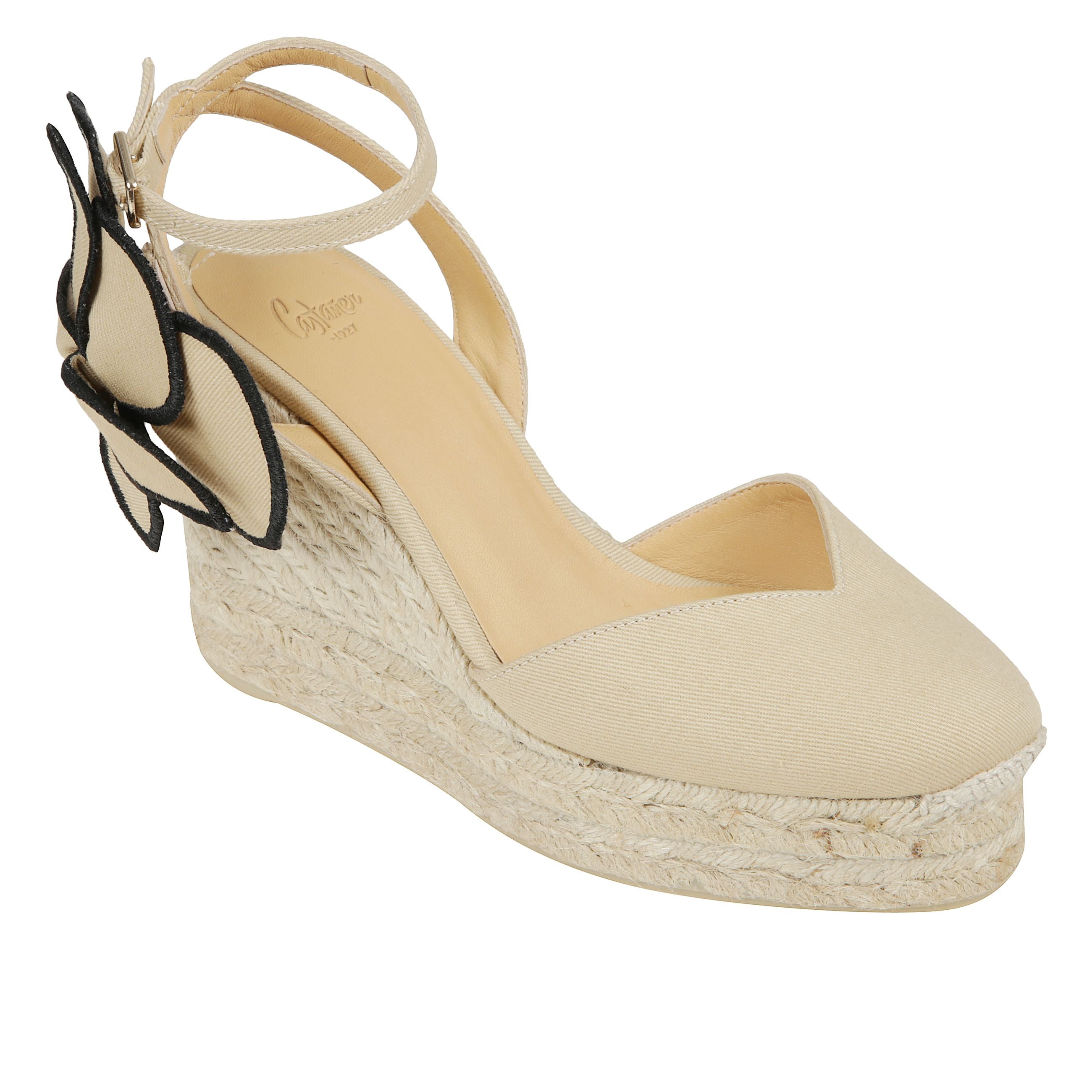 Espadrillas alta caratterizzata da tomaia in cotone, soletta con stampa logo, punta tonda, chiusura alla caviglia con lacci, dettaglio fiore laterale e tacco a zeppa in raffia.