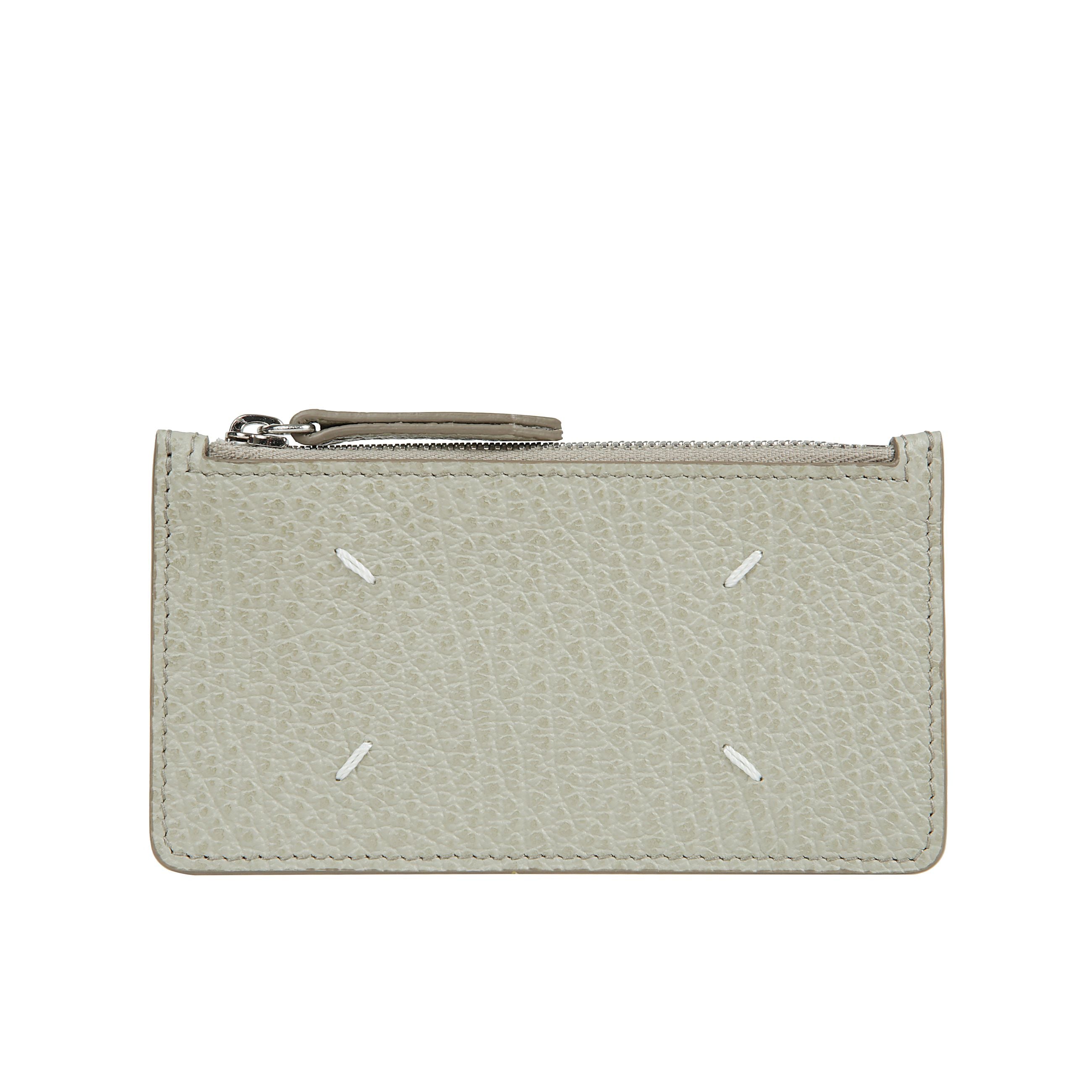 Portafoglio-portacarte in pelle martellata, con tasca a zip per le monete e cinque scomparti portatessere. numeric logo visibile allâinterno. sul retro, spiccano four stitches, caratteristica indiscussa di maison margiela : lâopposto di unâetichetta