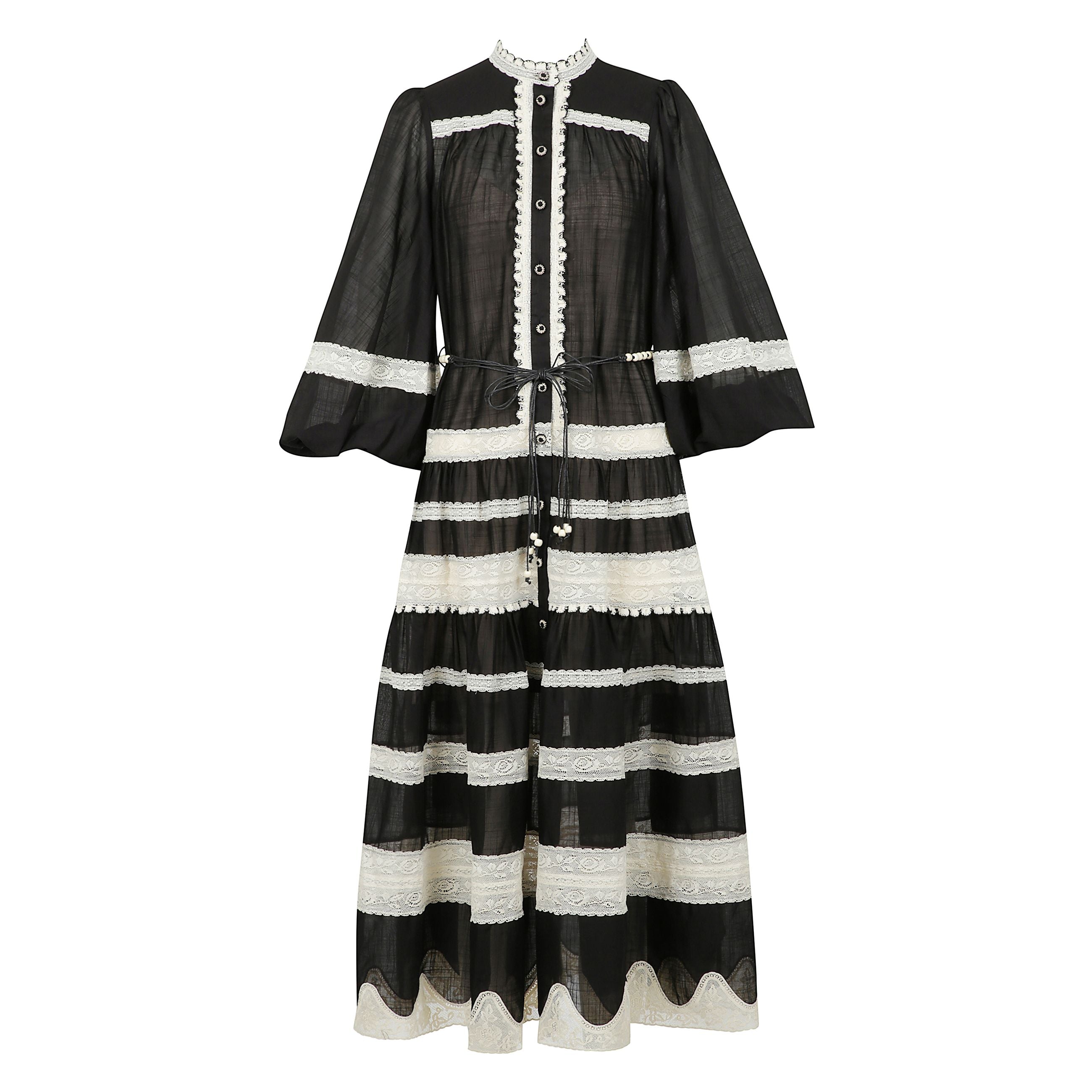 Abito in pizzo con maniche a sbuffo rhiannon in nero e crema. abito in cotone a sezioni con finiture allâuncinetto, collo alto, maniche a sbuffo con polsini elastici e bottoni al centro sul davanti.