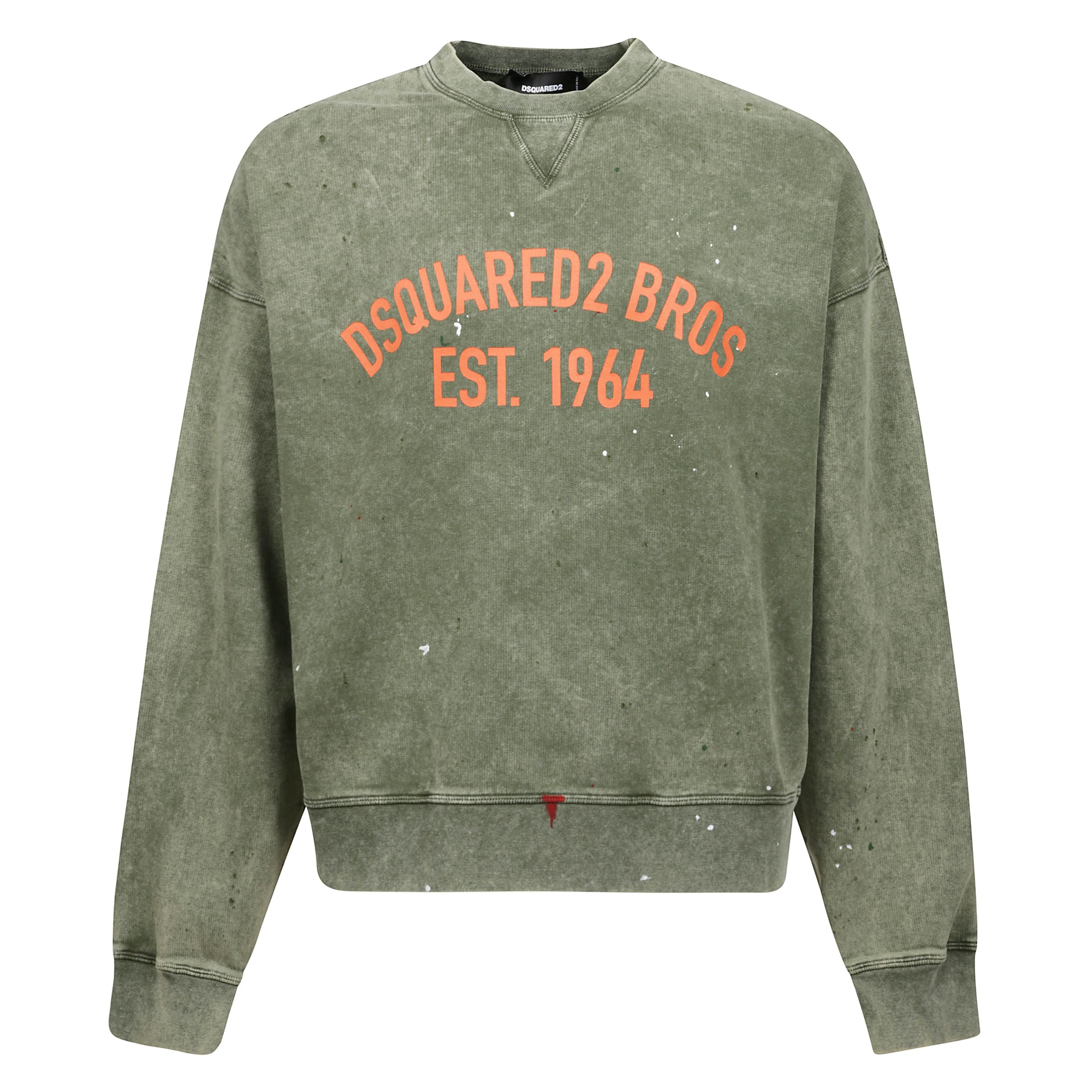 Felpa di dsquared2 realizzata in jersey di cotone color verde oliva con trattamento vintage washed e schizzi di colore. caratterizzata da scollatura a giro, maniche lunghe, bordi a costine e fondo dritto. completa il design la stampa dsquared2 bros fronta