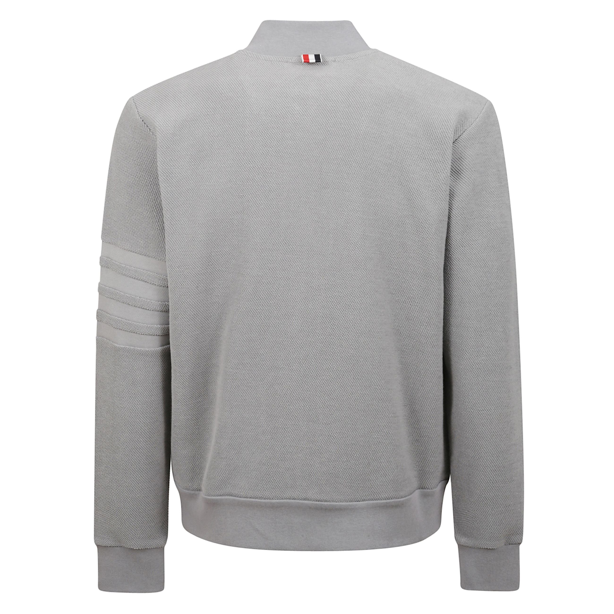 Felpa in cotone con chiusura frontale a zip. tasche oblique a filetto laterali. dettaglio a 4 barre sulla manica sinistra e patch con firma thom browne vicino all'orlo frontale. passante in grosgrain a righe sul retro.