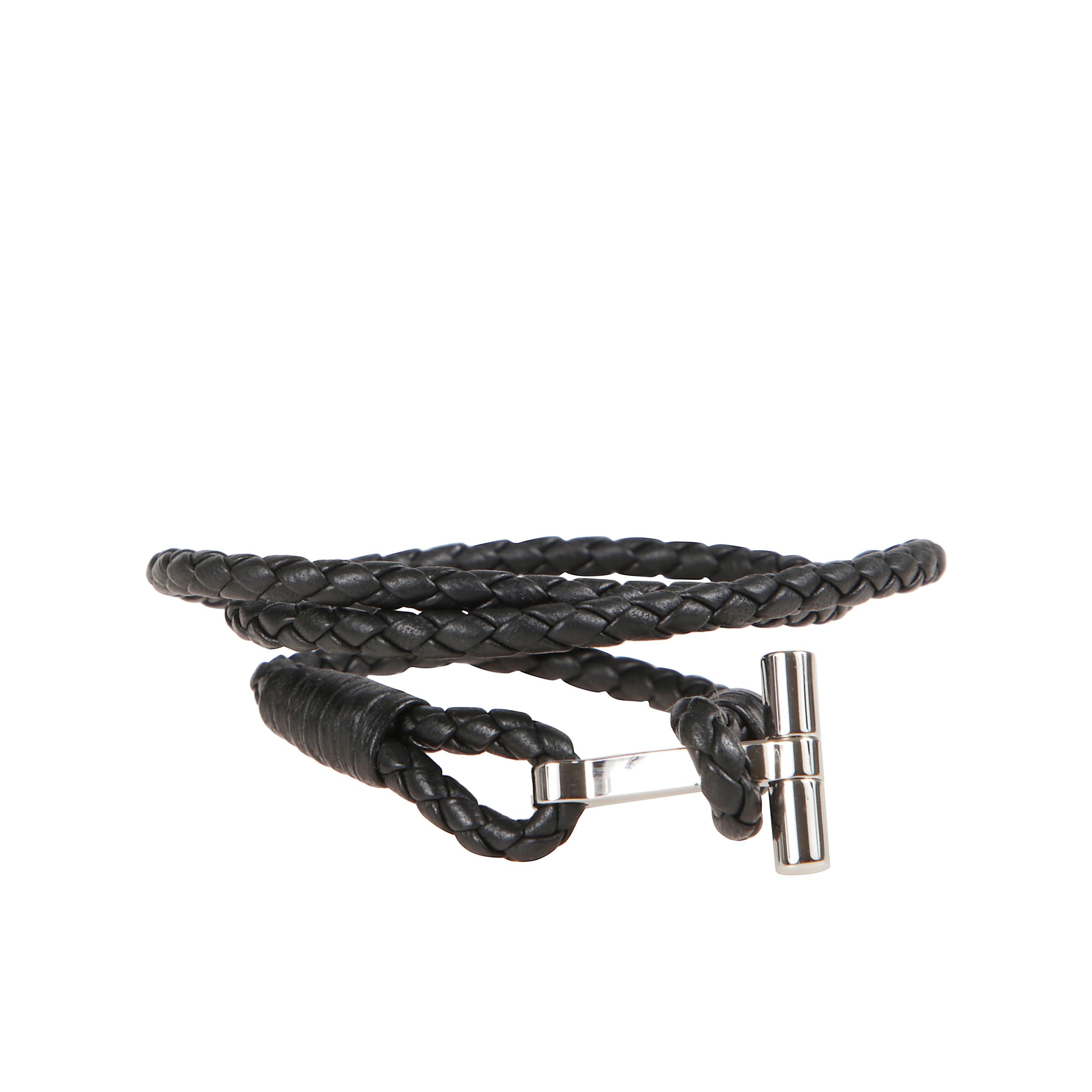 Bracciale in pelle a fascia intrecciata. chiusura ad alamaro con placca in bronzo metallizzato che riporta il simbolo tom ford.