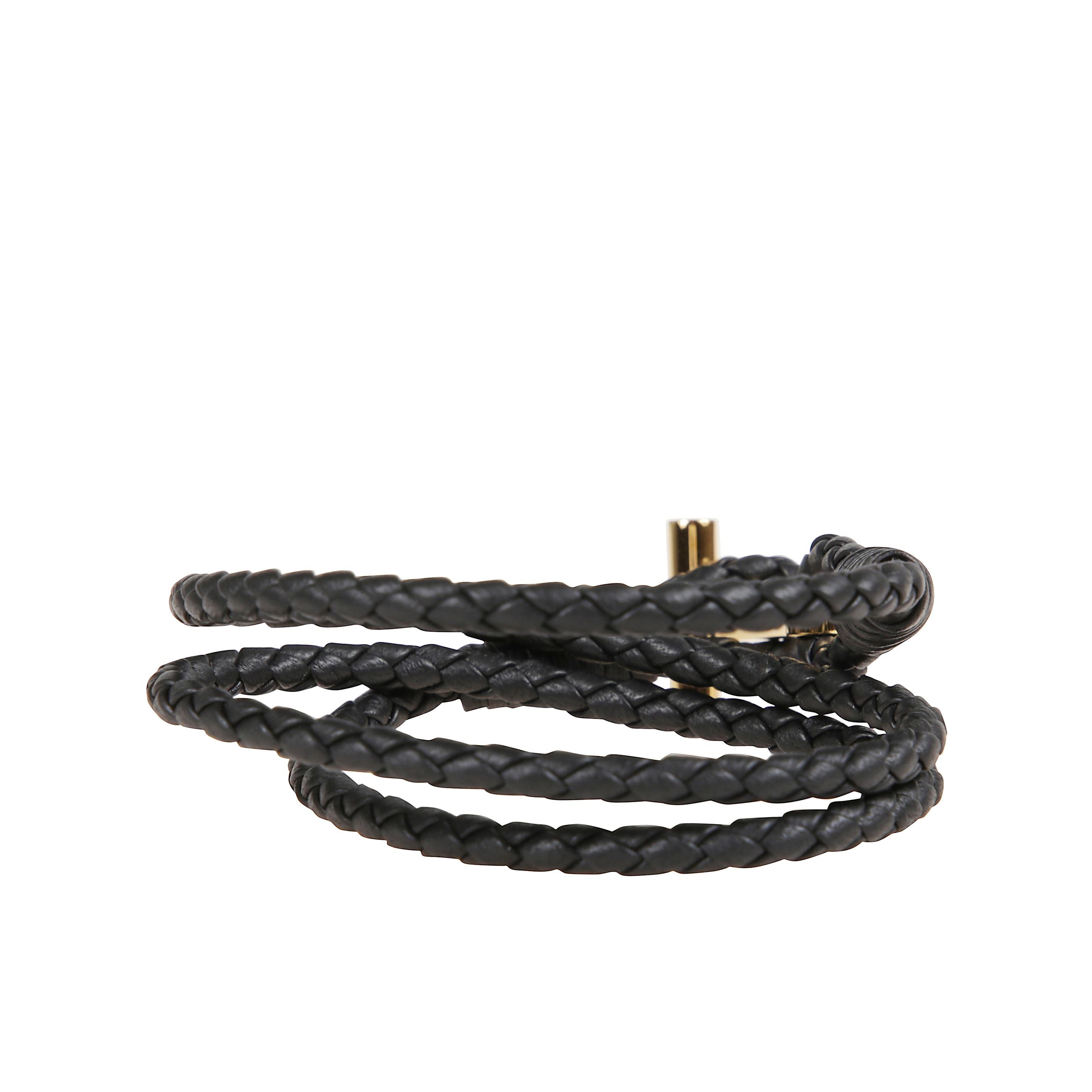 Bracciale in pelle a fascia intrecciata. chiusura ad alamaro con placca in bronzo dorato che riporta il simbolo tom ford.