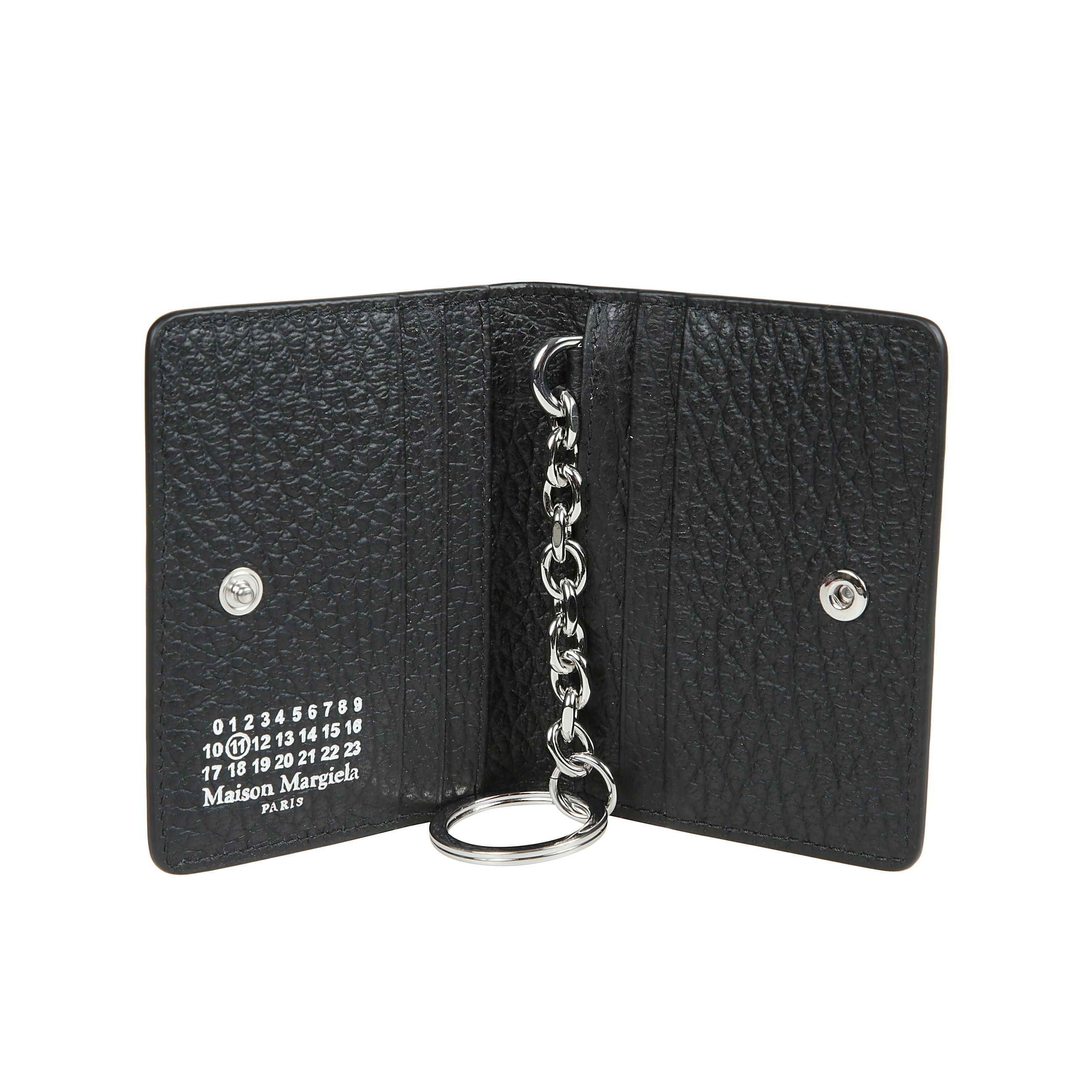 Portacarte in pelle martellata, con portachiavi, bottone automatico di chiusura e vari scomparti portatessere. sul retro, spiccano four stitches, caratteristica indiscussa di maison margiela : lâopposto di unâetichetta.