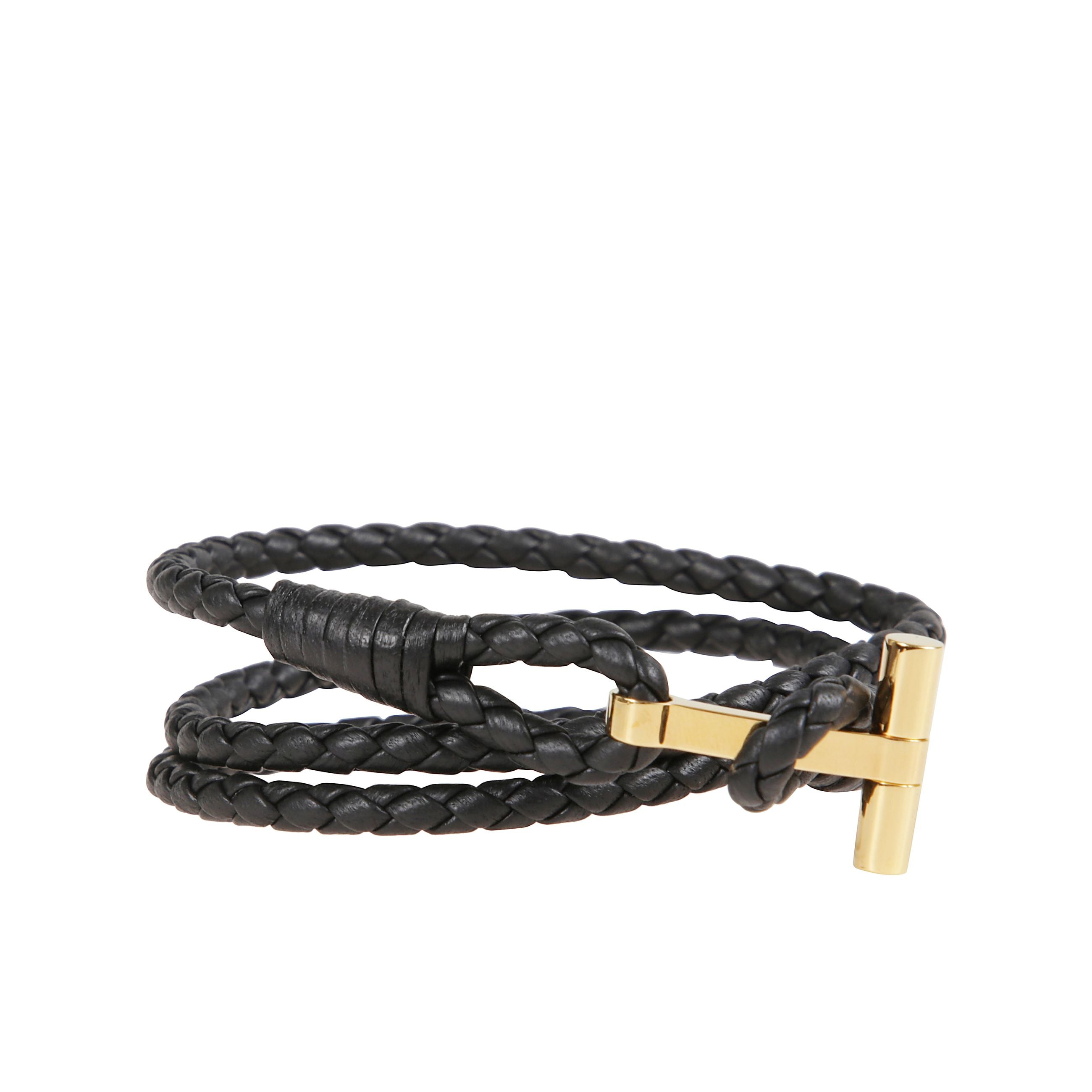 Bracciale in pelle a fascia intrecciata. chiusura ad alamaro con placca in bronzo dorato che riporta il simbolo tom ford.